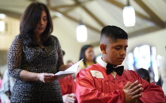Confirmation candidate Ayden Morocho kneels in prayer as his sponsor, Grace Esposito, stands behind him during a confirmation Mass on May 5, 2022, at Holy Family Church in Queens, New York. (CNS/Gregory A. Shemitz)